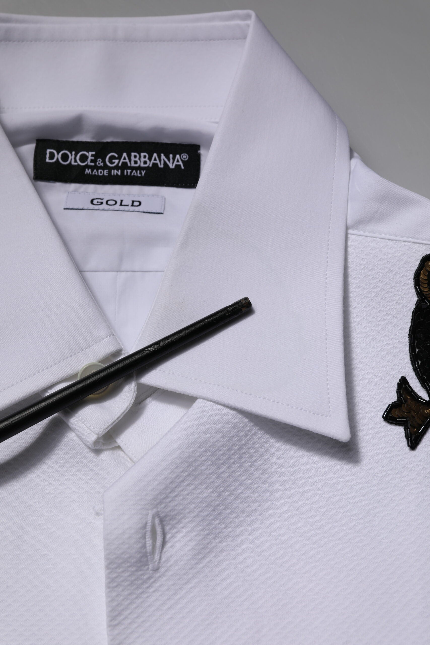 Chemise formelle blanche pour homme Dolce & Gabbana avec embellissements dorés, détails élégants et finition raffinée.