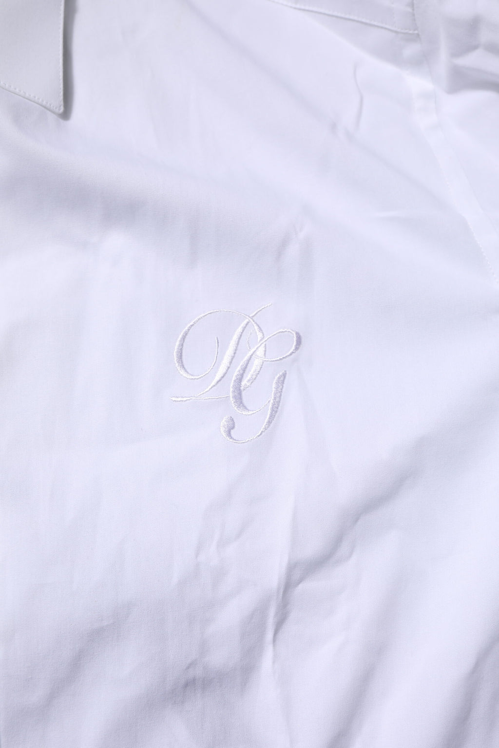 Chemise formelle blanche en coton Dolce & Gabbana avec manches longues et détails dorés visible sur l'image.