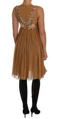Robe longue en soie cristal dorée Dolce & Gabbana avec coupe évasée et détails élégants, portée pour une occasion sophistiquée.