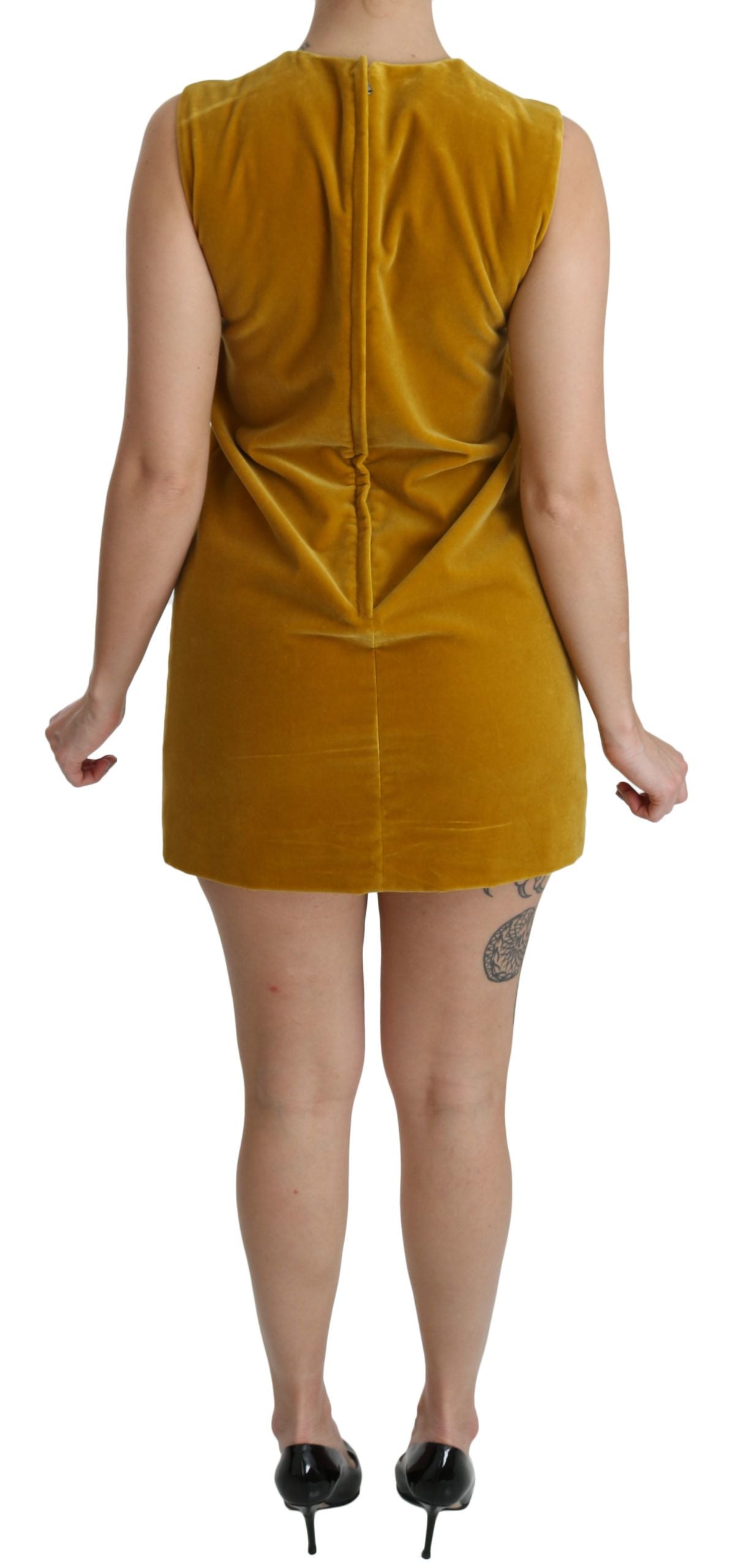 Robe courte en velours moutarde Dolce & Gabbana, robe ajustée et stretch, en tissu élégant, portée sur un fond neutre.
