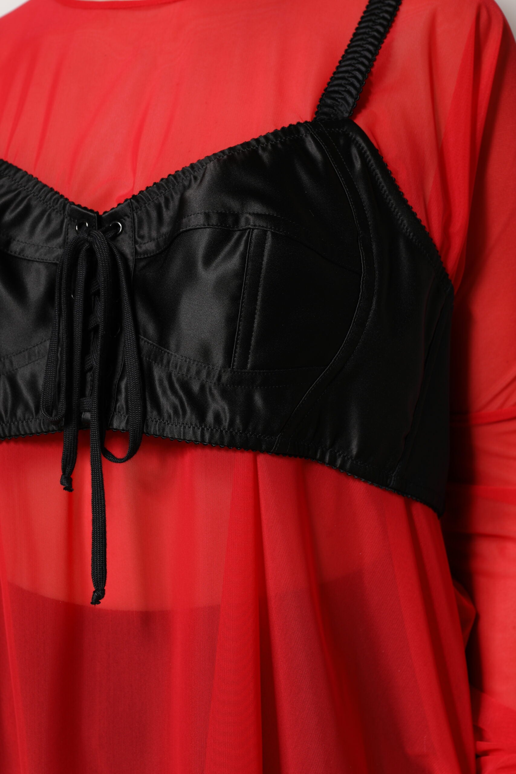 Haut Dolce & Gabbana en dentelle rouge et noire avec bustier, manches longues et détails élégants.