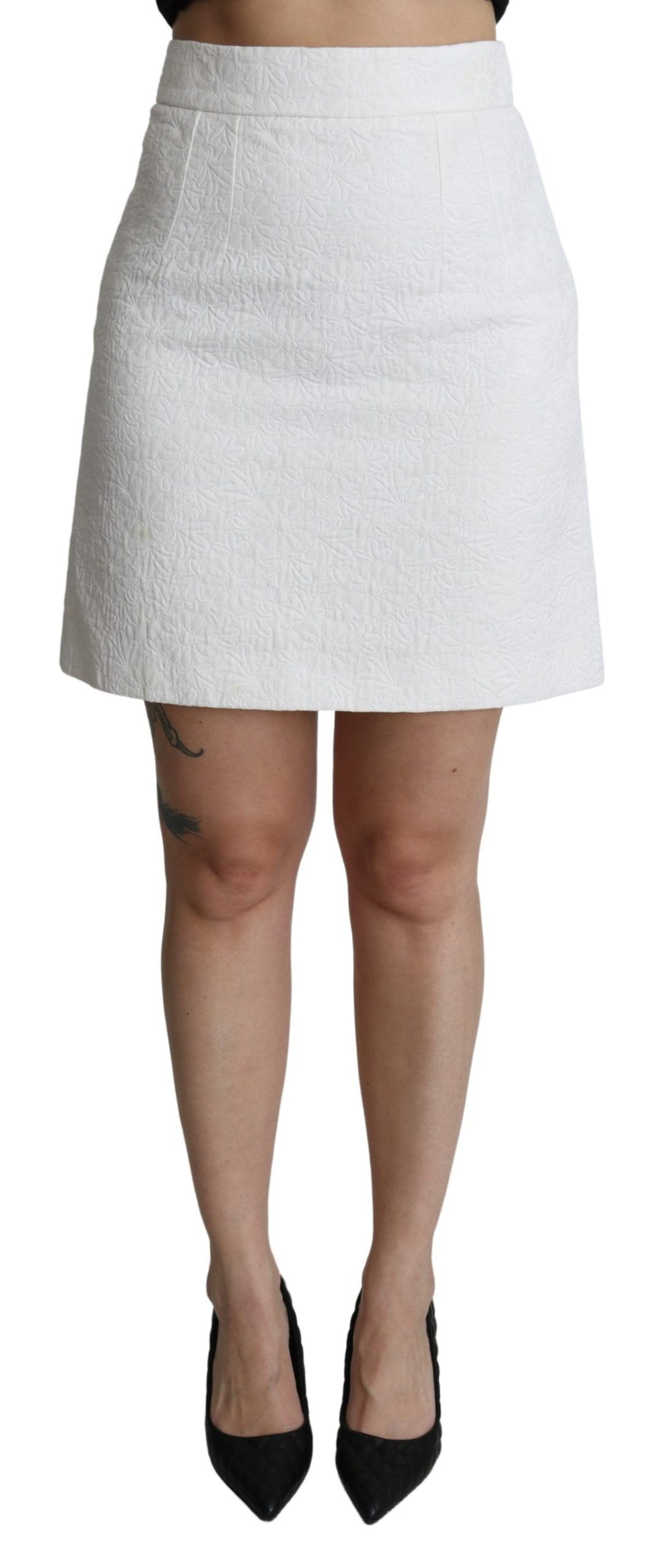 Jupe courte en brocart blanc à taille haute avec motifs floraux, par Dolce & Gabbana, vue de face.