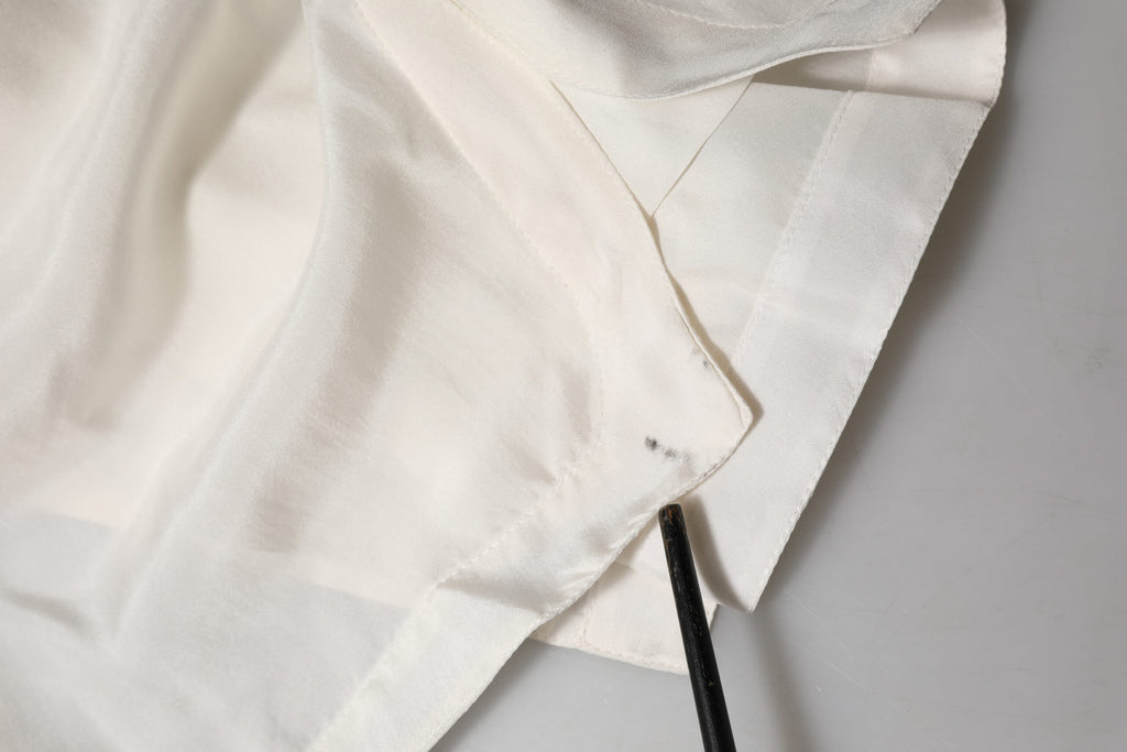 Chemise polo en soie blanche Dolce & Gabbana avec boutons, vue de face sur un fond neutre.