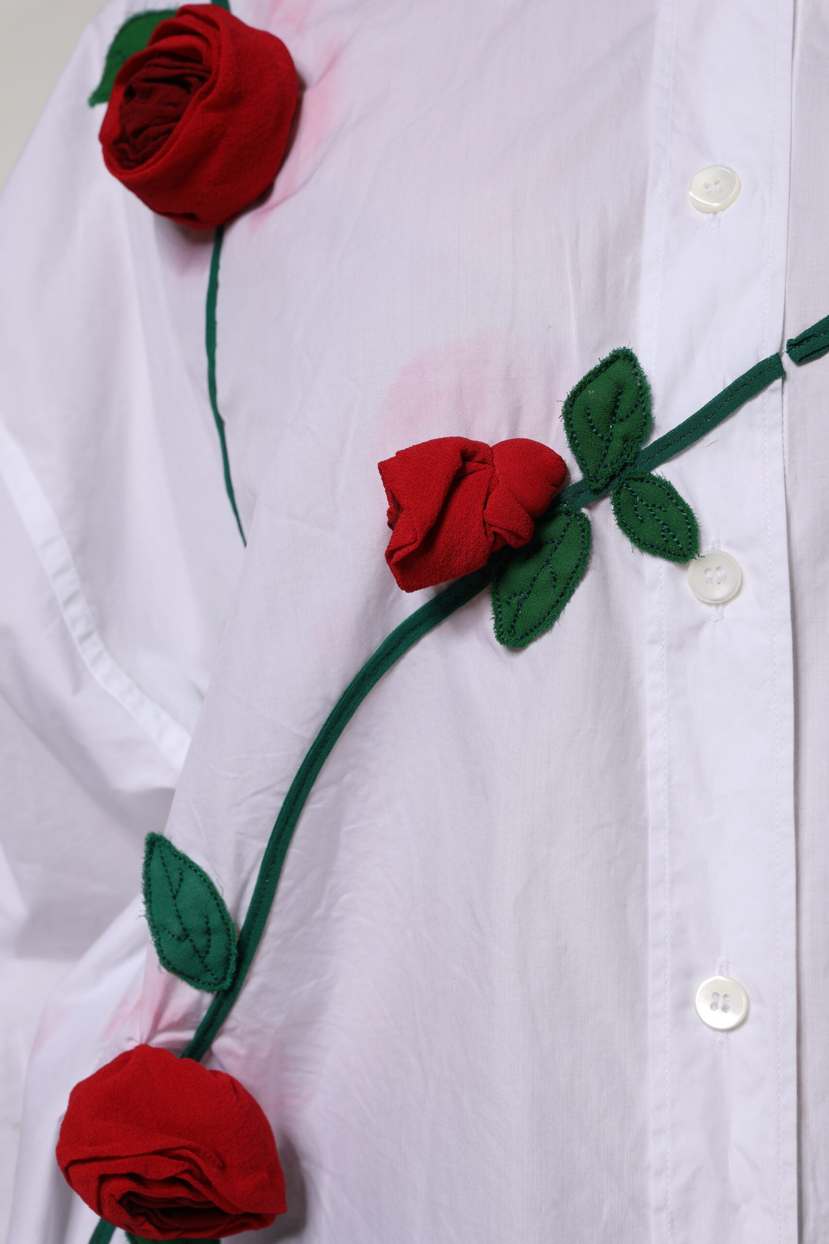Chemise blanche en coton avec appliqués floraux Dolce & Gabbana, style élégant et sophistiqué, visible sur le haut du vêtement.
