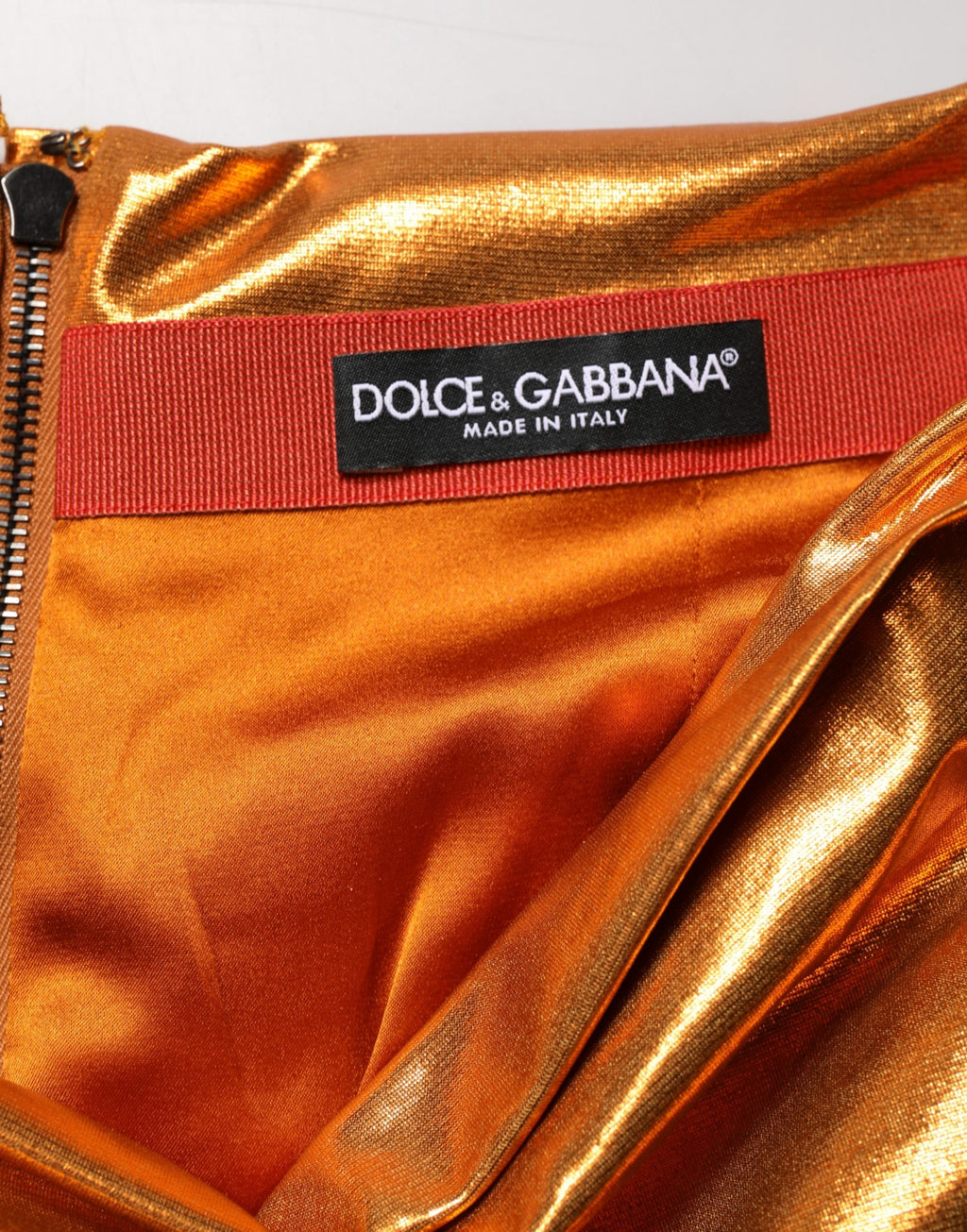 Jupe courte moulante en lamé orange métallique avec fronces, de la marque Dolce & Gabbana, vue de face.
