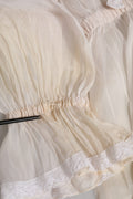 Chemisier Dolce & Gabbana en soie et coton blanc avec col ascot élégant, détail de la blouse sophistiquée et raffinée.
