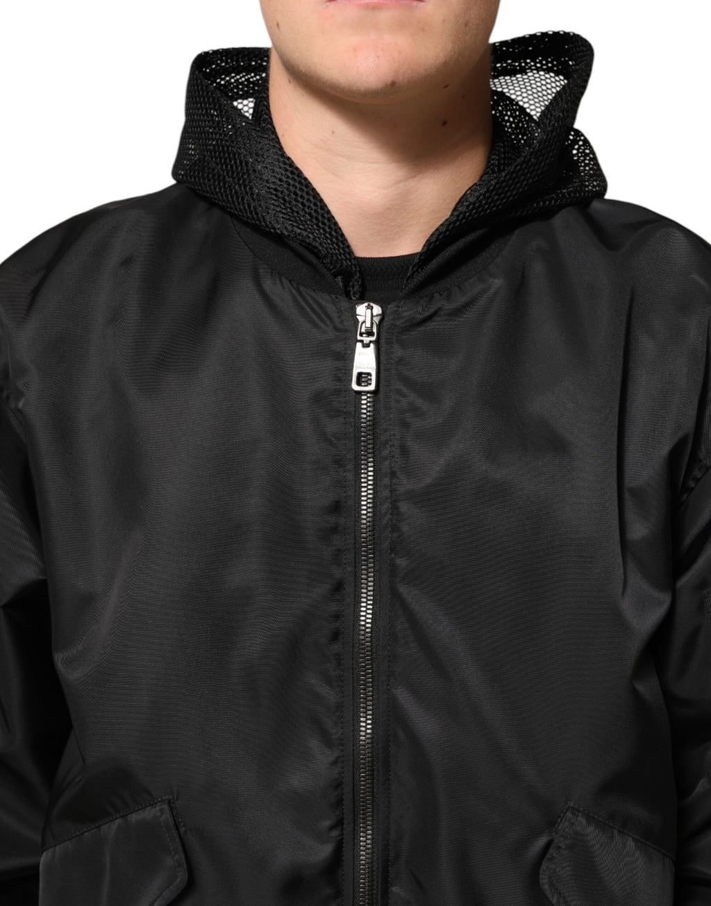 Veste homme bomber Dolce & Gabbana en nylon noir avec capuche et fermeture éclair complète, détail de la poche frontale.