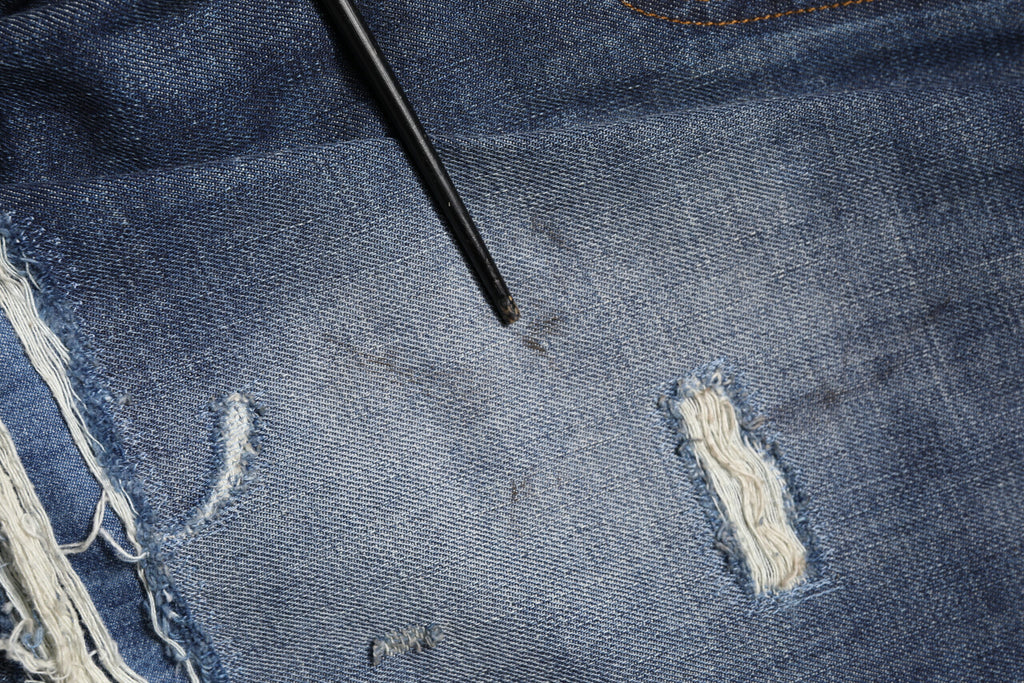 Jeans homme en coton délavé et usé de Dolce & Gabbana, style tattered, bleu clair, détails déchirés et usés.