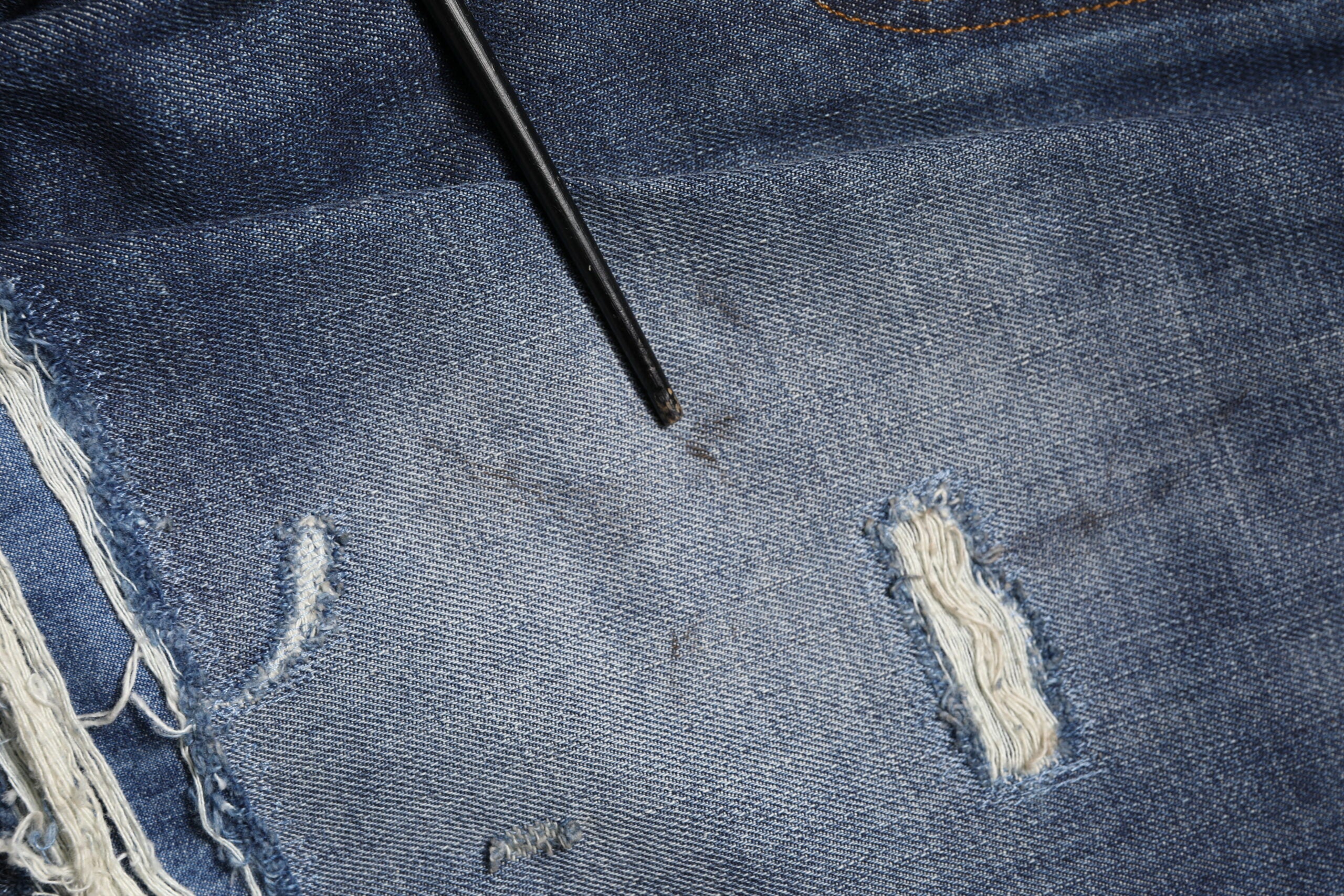 Jeans homme en coton délavé et usé de Dolce & Gabbana, style tattered, bleu clair, détails déchirés et usés.