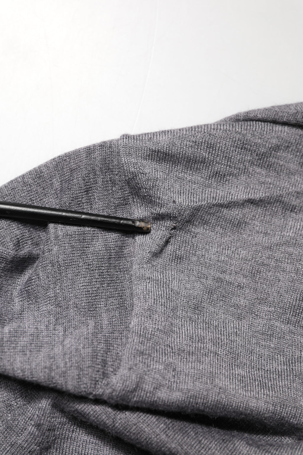 Pull en cachemire gris Dolce & Gabbana pour homme avec col en V, doux et élégant, porté sur un fond neutre.