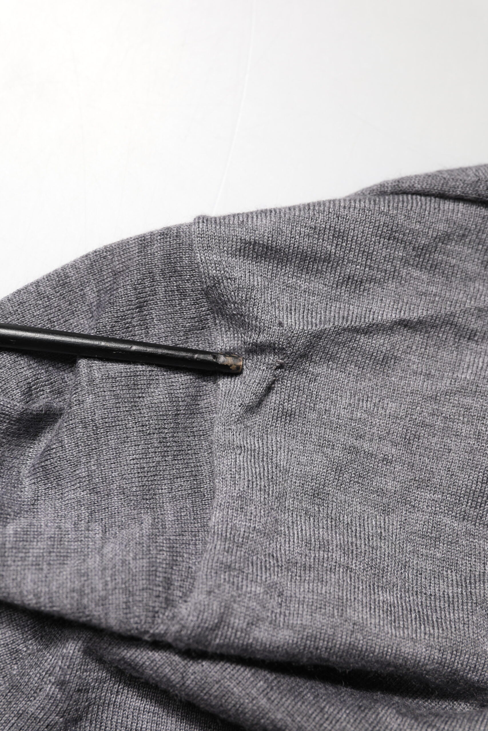 Pull en cachemire gris Dolce & Gabbana pour homme avec col en V, doux et élégant, porté sur un fond neutre.