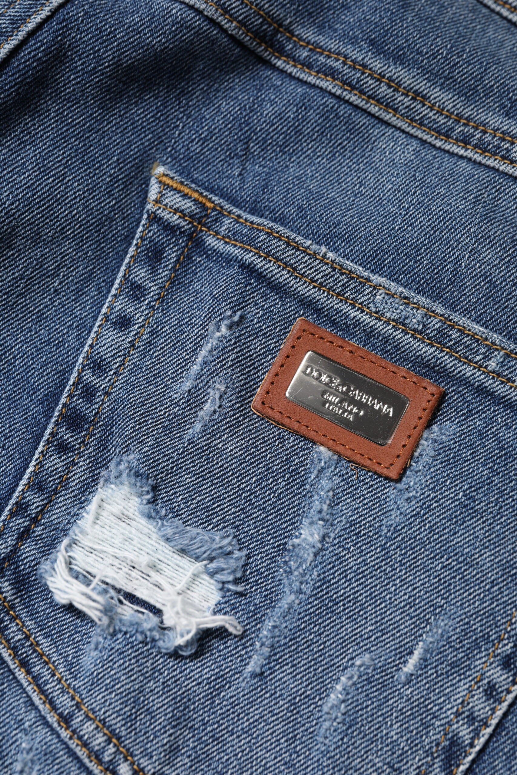 Jeans en denim bleu déchiré à taille basse de Dolce & Gabbana, coupe tendance et détails usés visibles sur l'image.