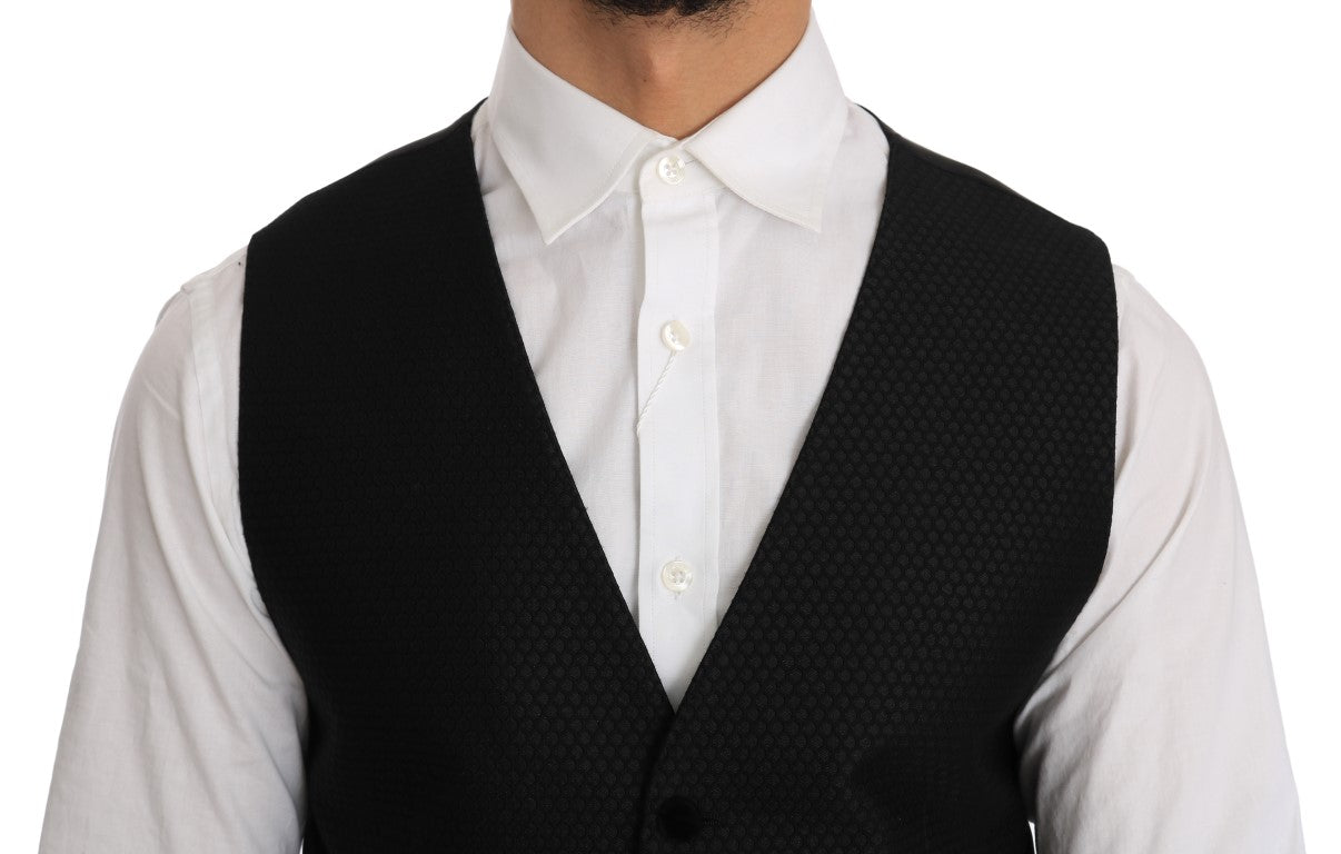 Gilet noir à motif pois Dolce & Gabbana avec détails élégants, porté sur un fond neutre, mettant en valeur le tissu et le design.