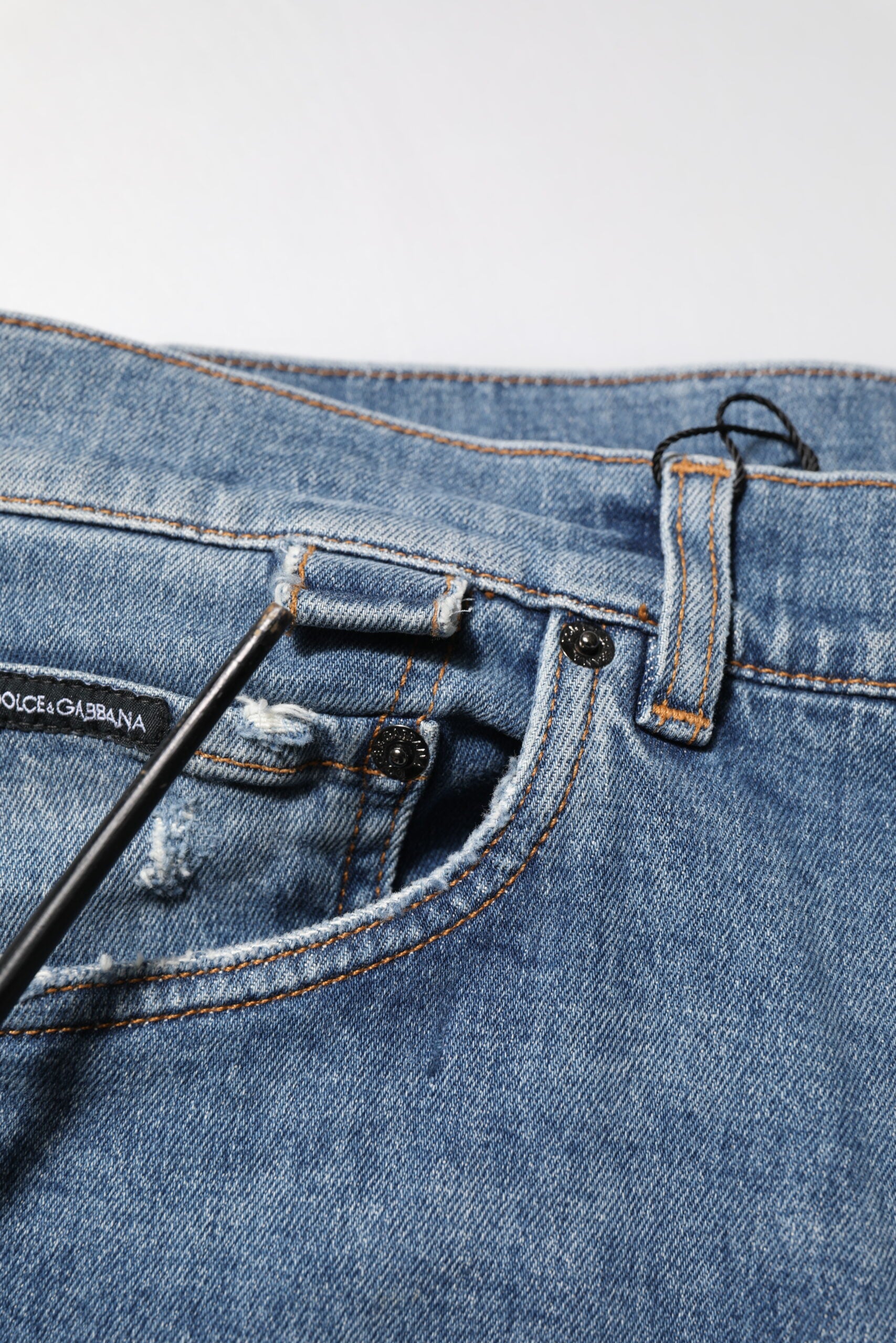 Jeans skinny en denim bleu Dolce & Gabbana avec déchirures, logo et coupe ajustée, visibles sur l’image.