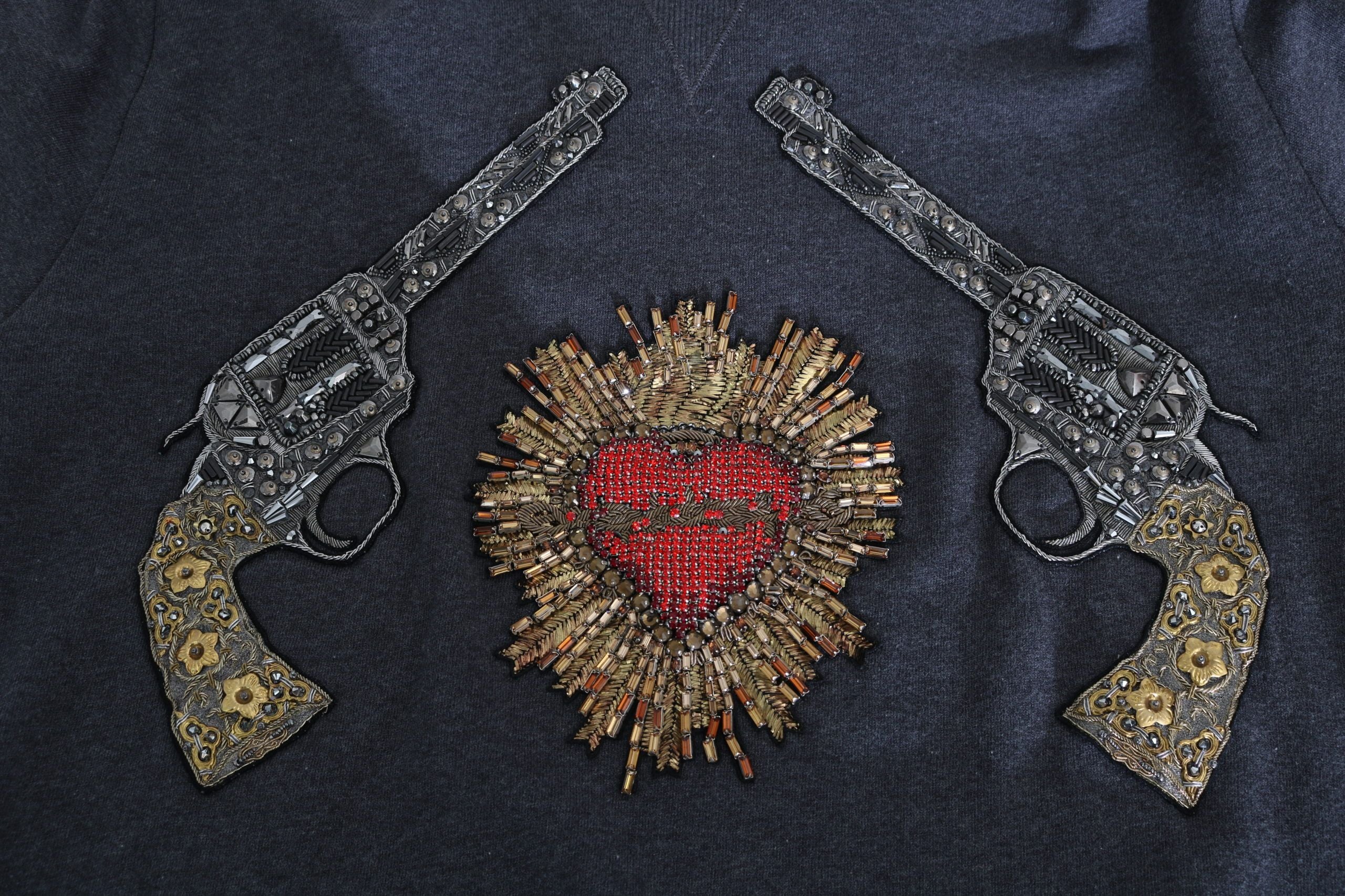 Sweat à capuche gris de Dolce & Gabbana avec cœur en cristal rouge et motif pistolet, style tendance et luxe.