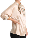 Blouse en soie stretch beige avec ruban Dolce & Gabbana, top élégant à manches longues et décolleté flatteur.