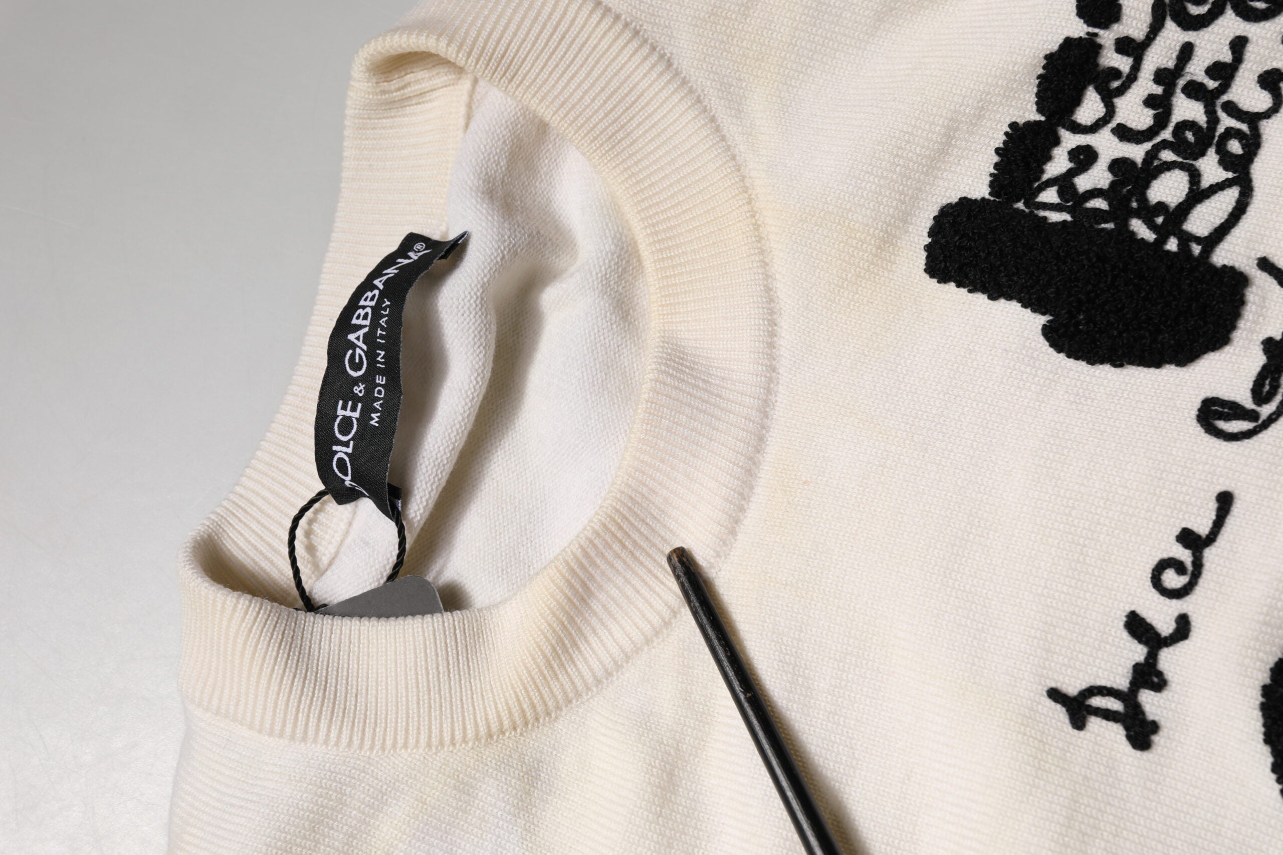 Pull blanc en laine vierge Dolce & Gabbana avec logo graphique sur le col, style décontracté et élégant.