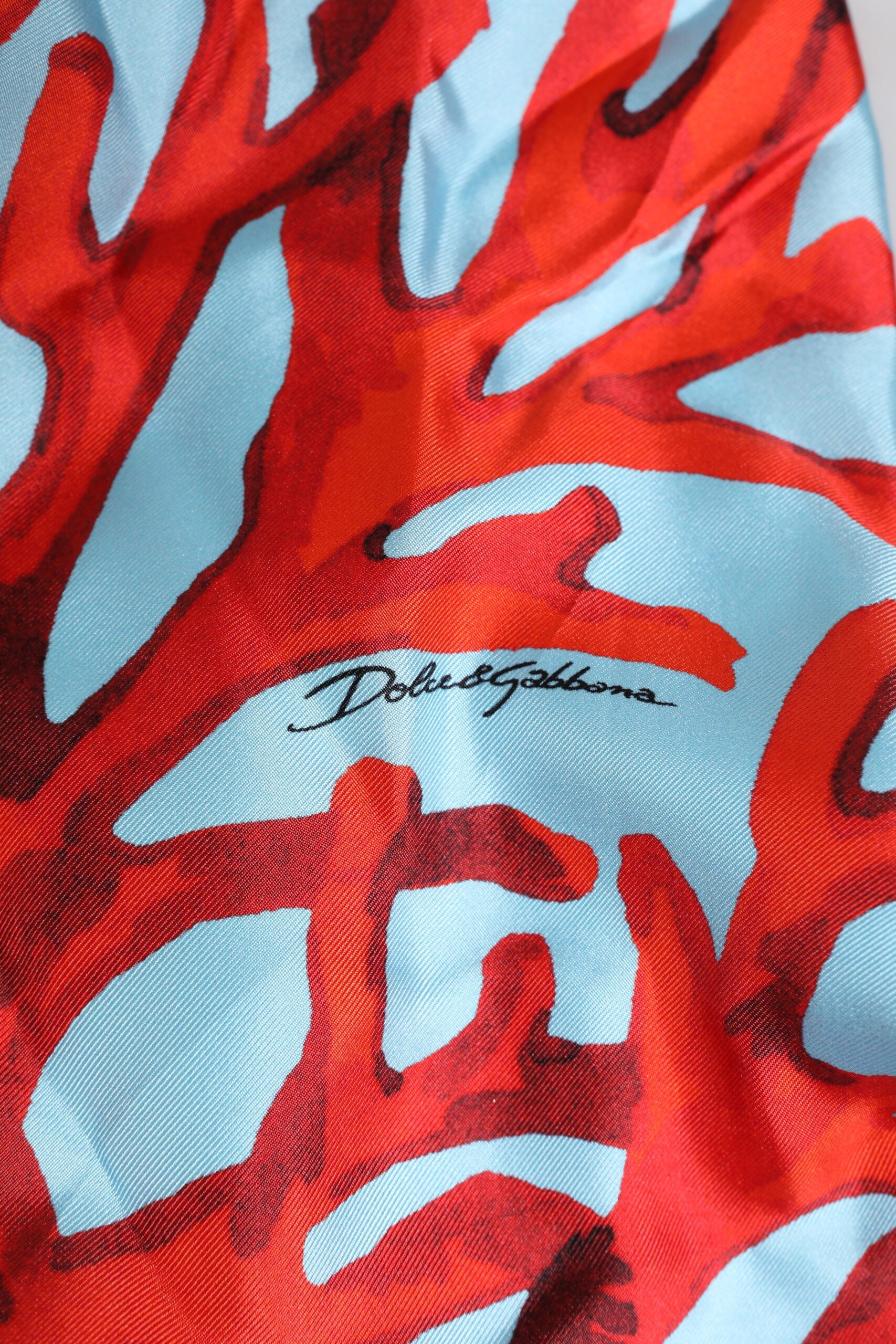 Robe courte Dolce & Gabbana à motif corail bleu et rouge, en tissu léger, avec ceinture à la taille.