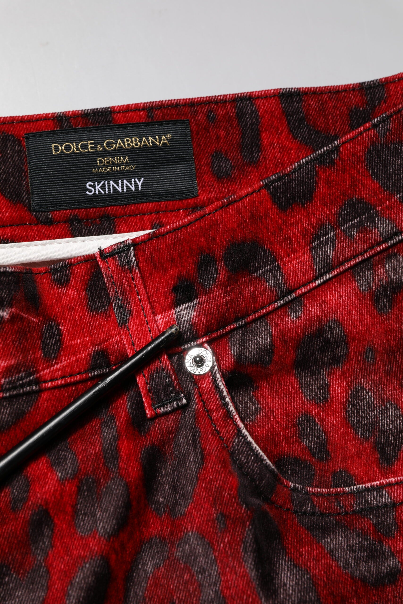 Jeans skinny en coton Dolce & Gabbana à motif léopard rouge, style denim ajusté, visible en détail dans l'image.