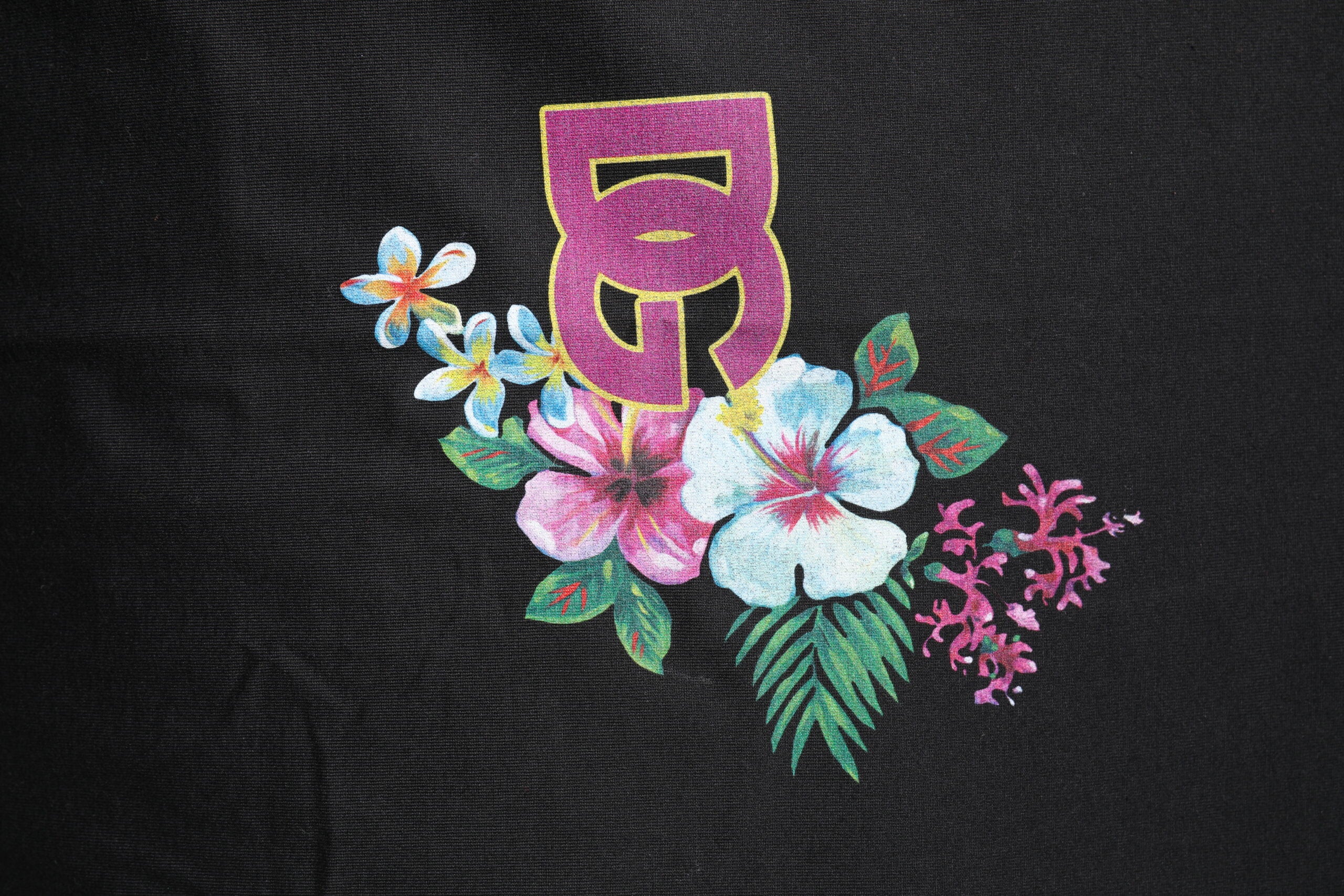 T-shirt à col rond noir Dolce & Gabbana avec imprimé floral DG, visible en gros plan sur fond neutre.