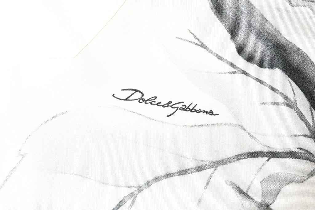 Écharpe blanche en soie avec illustration botanique noire et grise et signature dolce & gabbana en cursive élégante