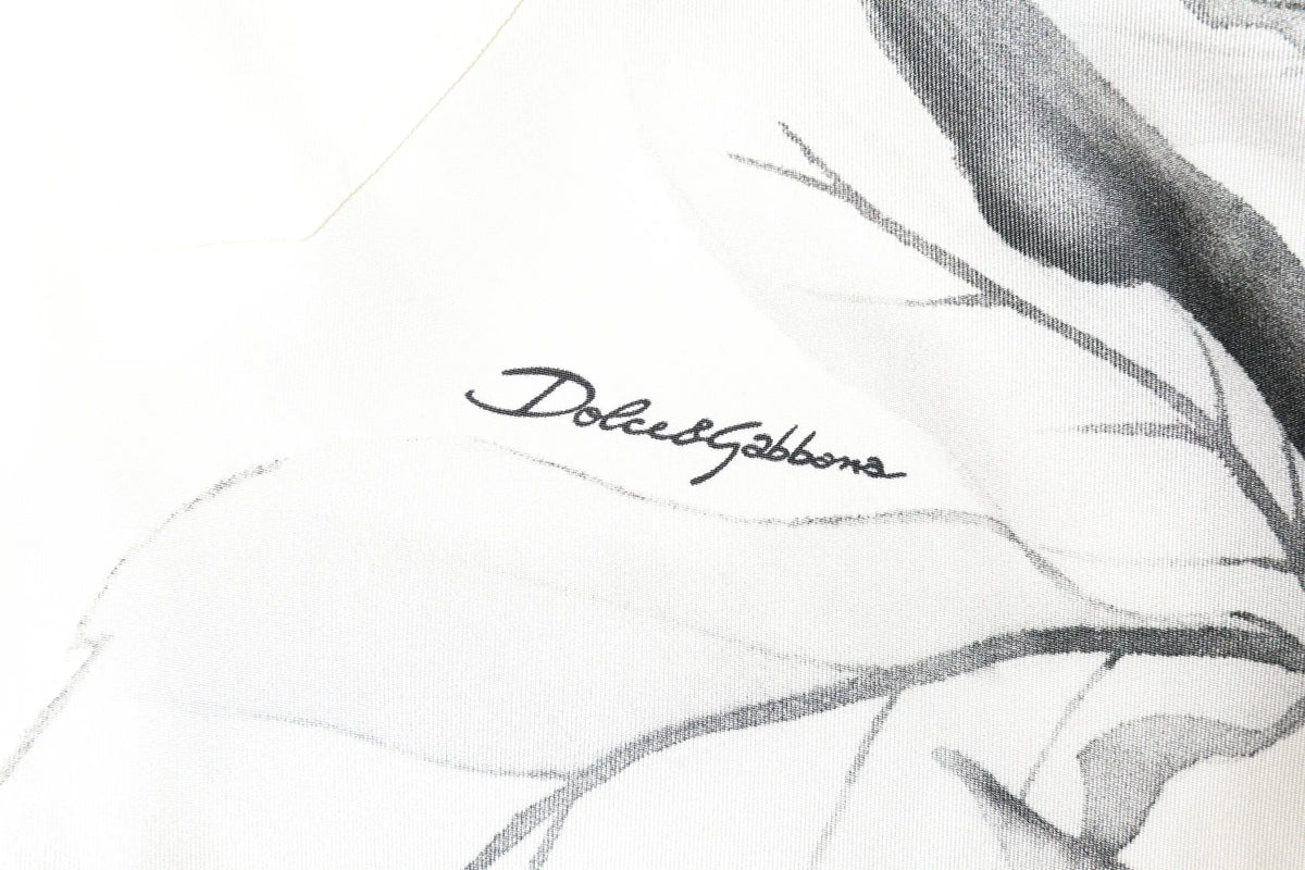Écharpe blanche en soie avec illustration botanique noire et grise et signature dolce & gabbana en cursive élégante
