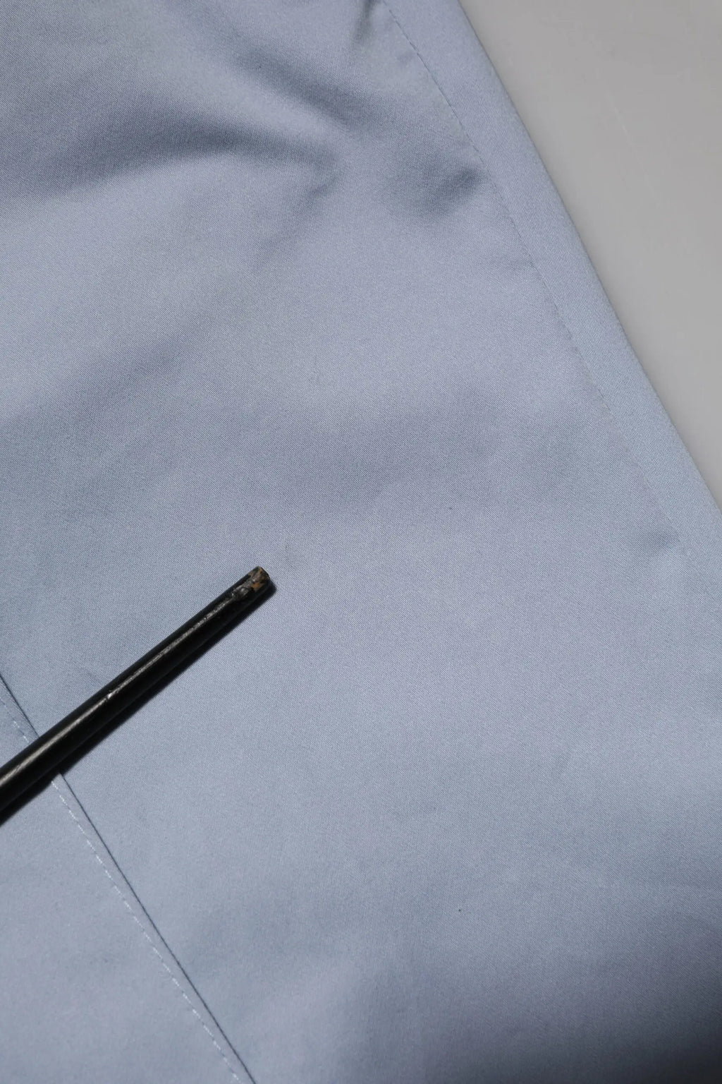 Bâtonnets noirs avec pointe légèrement usée reposant sur un tissu bleu clair proche d’un pantalon homme dolce gabbana light blue en coton à taille élastique avec cordon