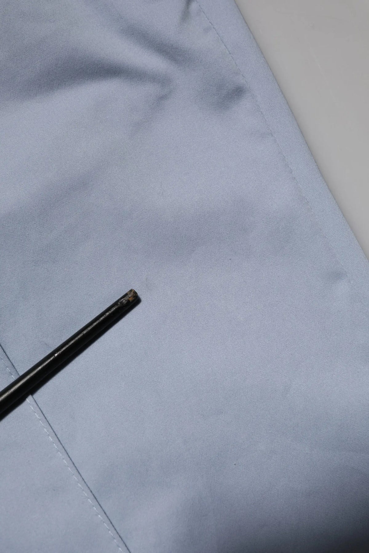 Bâtonnets noirs avec pointe légèrement usée reposant sur un tissu bleu clair proche d’un pantalon homme dolce gabbana light blue en coton à taille élastique avec cordon