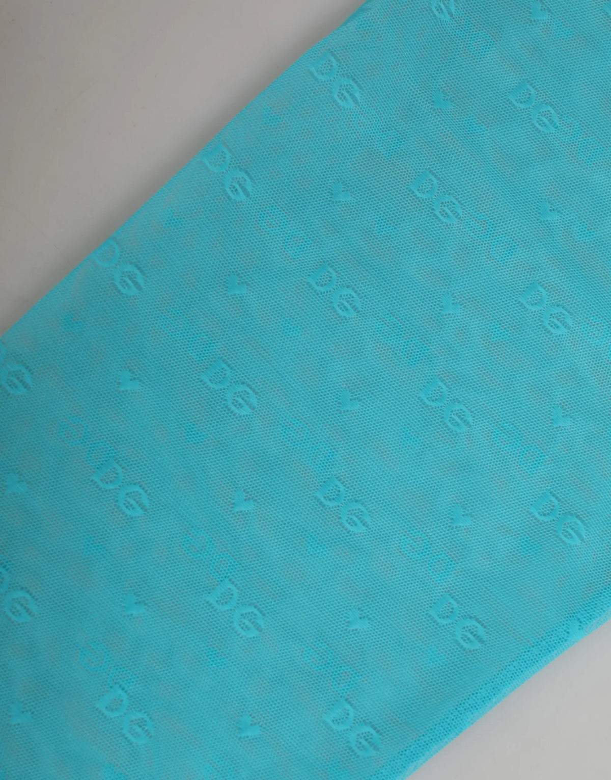 Foulard en tissu turquoise avec motif logo embossé subtil associé au pantalon moulant dentelle bleu clair dolce gabbana