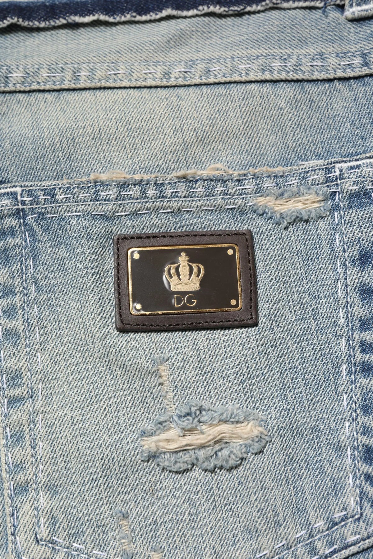 Patch en cuir noir avec couronne dorée et logo dg cousue sur le dos d un jean denim délavé clair droit Dolce Gabbana