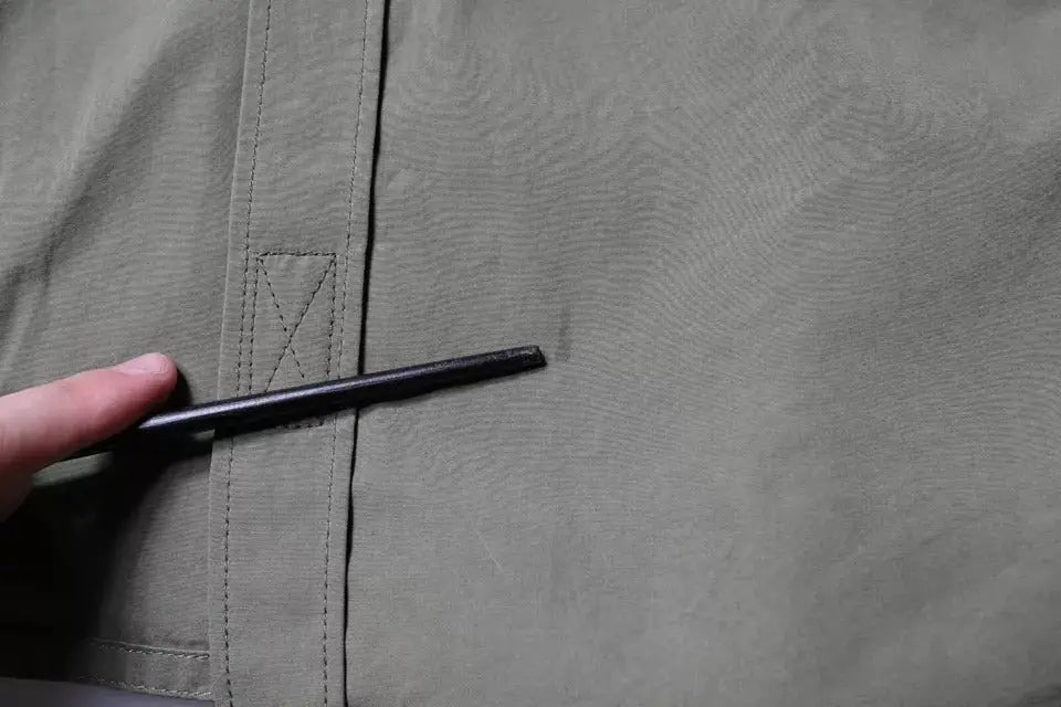 Un stylo noir tenu contre la couture dun manteau Dolce & Gabbana kaki en coton style militaire