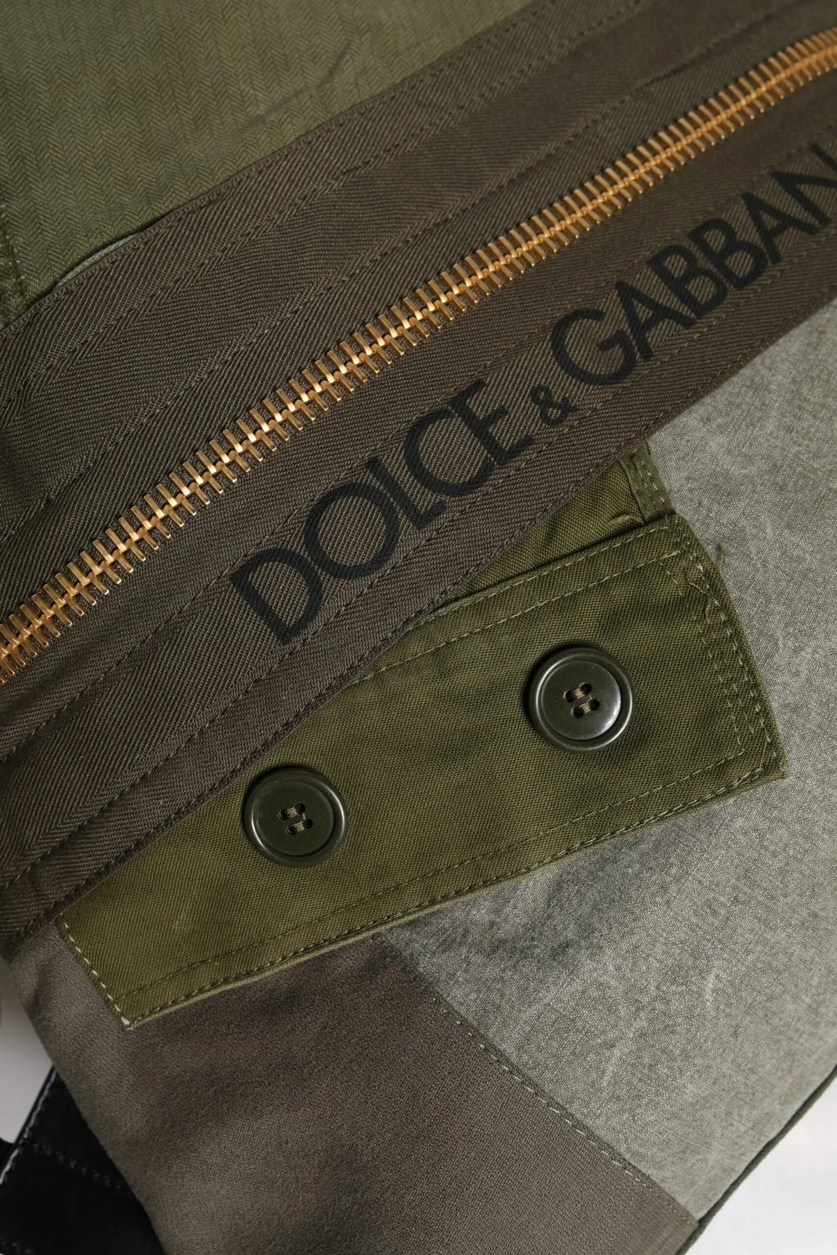 Veste olive verte dolce gabbana avec fermeture éclair dorée et boutons assortis affichée avec sac à dos patchwork militaire