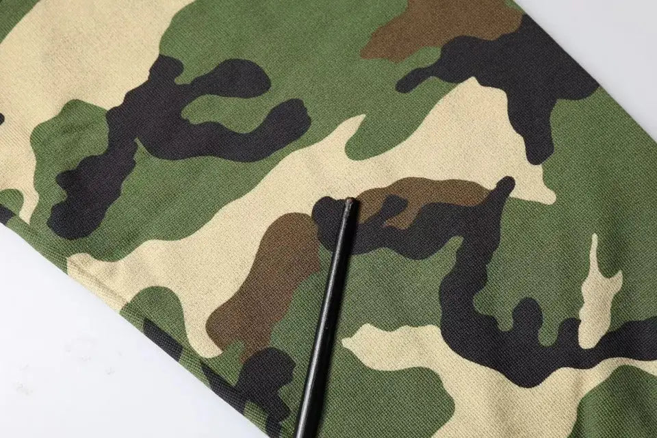 Un objet cylindrique noir posé en diagonale sur un sweat multicolore camouflage dolce gabbana