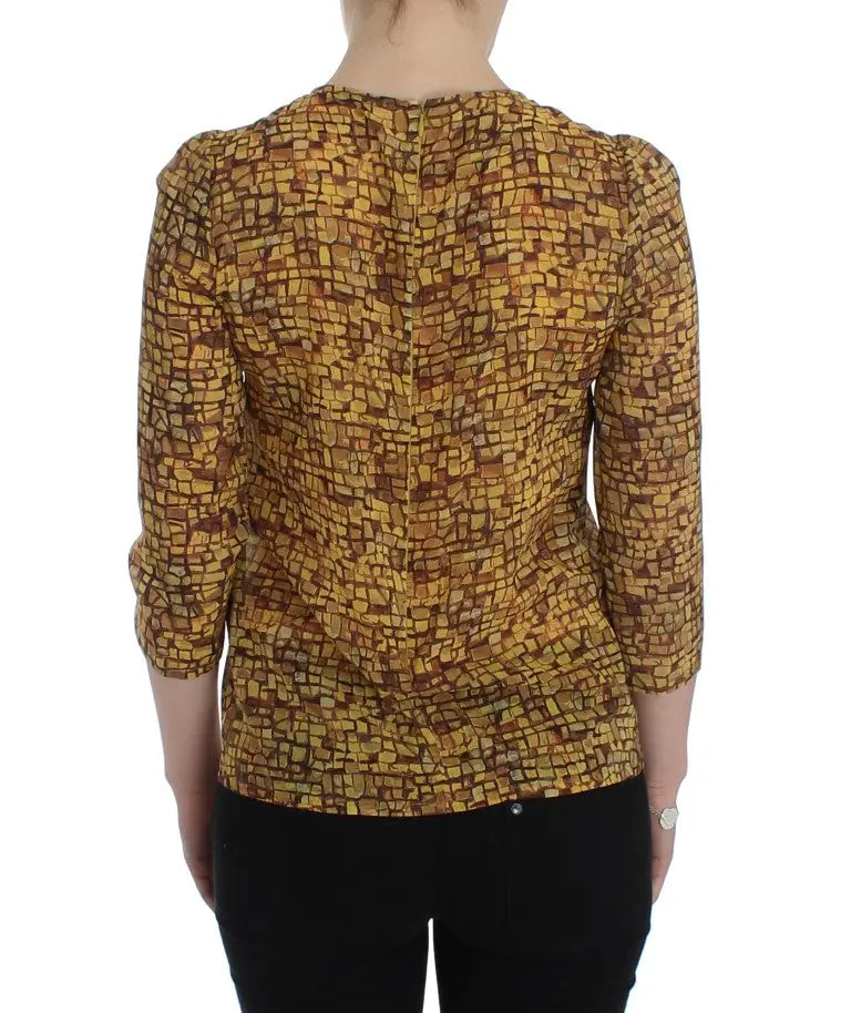 Une femme porte un blouse dolce & gabbana en soie multicolore motif mosaïque jaune et marron manches trois quarts