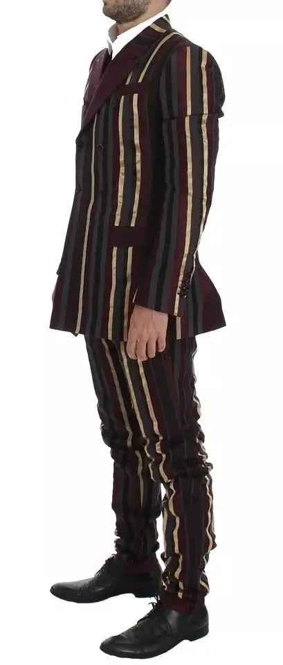 Un homme portant un costume dolce & gabbana multicolore à rayures verticales bordeaux noir et or slim fit avec gilet