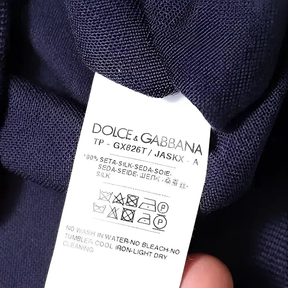 Étiquette en soie bleu marine dolce gabbana avec instructions d’entretien multilingues pour pull col v en soie