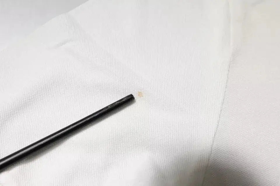 Objet cylindrique noir posé sur tissu blanc avec polo col coton off white crown de Dolce & Gabbana