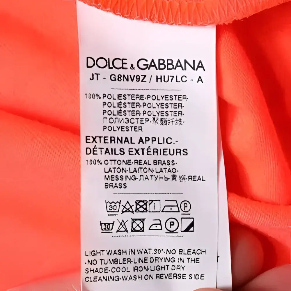 Étiquette d entretien blanche dolce & gabbana avec texte noir montrant marque et composition tissu d un t shirt orange en polyester