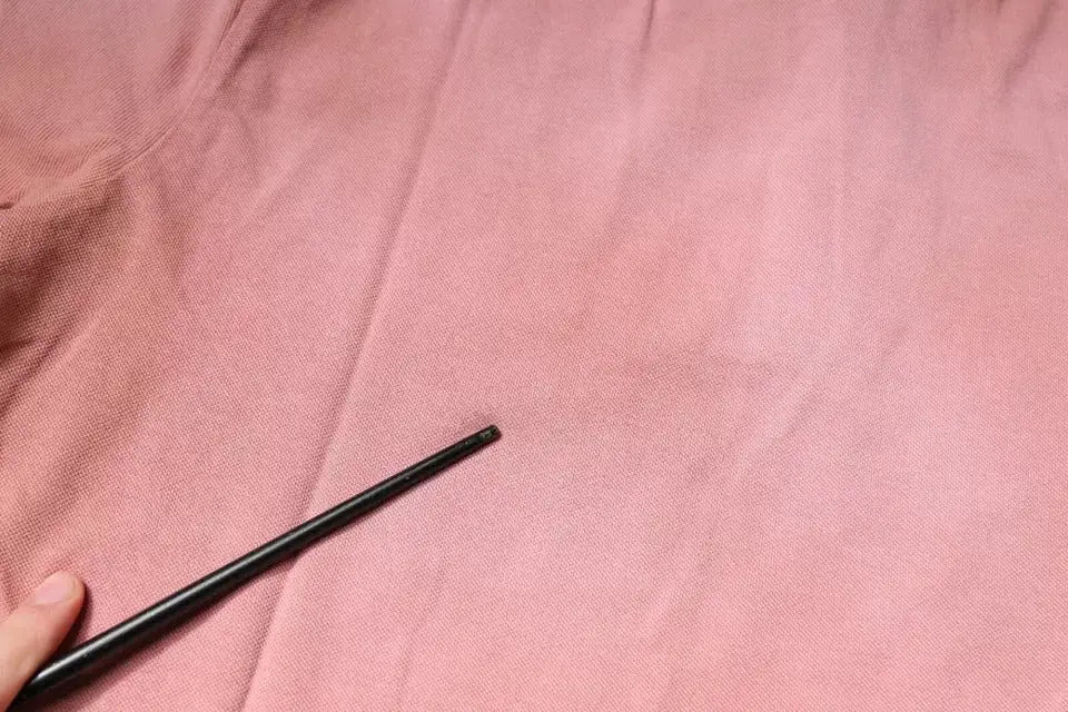 Main noire cylindrique tenue dans une main contre tissu rose du polo dolce & gabbana pink crown col à manches courtes