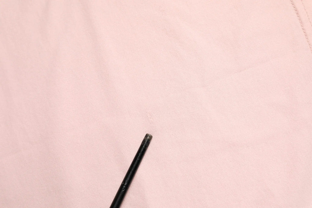 Crayon noir reposant sur tissu rose pâle du t-shirt en coton dolce gabbana dg 84 motif sacré cœur