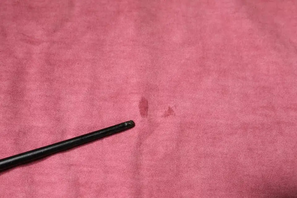 Objet cylindrique noir posé sur tissu rose du t shirt dolce et gabbana en coton avec logo rose