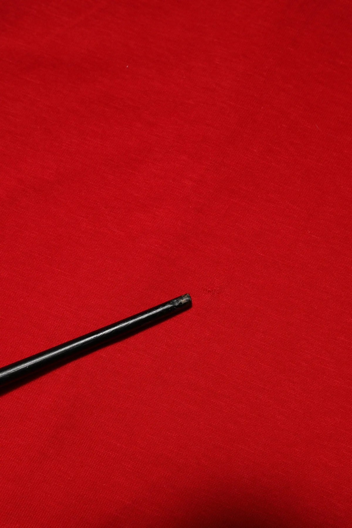 Stylo cylindrique noir à fini mat avec pointe légèrement usée présenté avec un t-shirt dolce & gabbana rouge col rond manches courtes casual