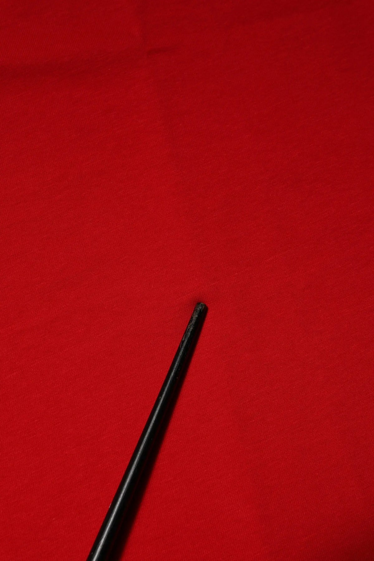 Objet cylindrique noir avec surface légèrement texturée et extrémité effilée pour le haut dolce gabanna rouge en coton