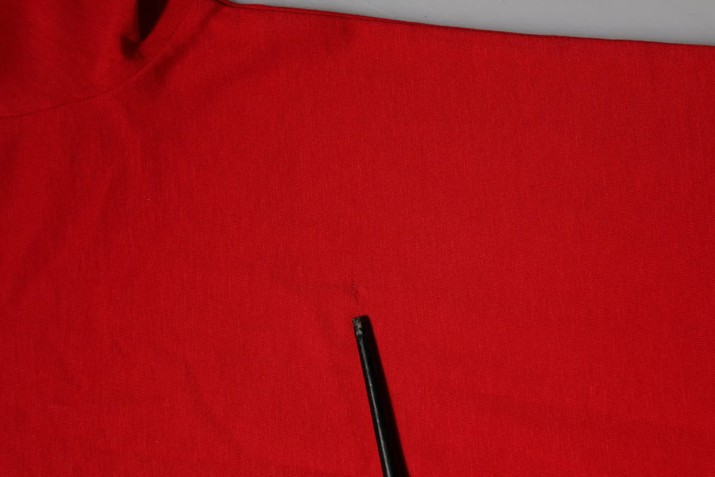 Un stylo noir posé en diagonale sur un t-shirt dolce & gabbana rouge col rond manches courtes en tissu vif