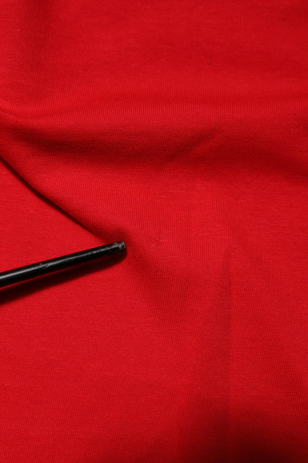 Objet cylindrique noir posé sur tissu rouge du t-shirt dolce & gabbana rouge à col rond et manches courtes