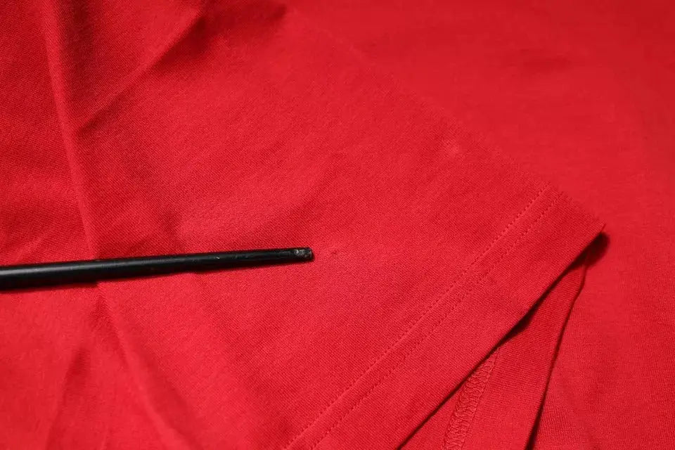 Objet cylindrique noir posé sur tissu rouge du t-shirt dolce & gabbana coton col rond avec logo rouge
