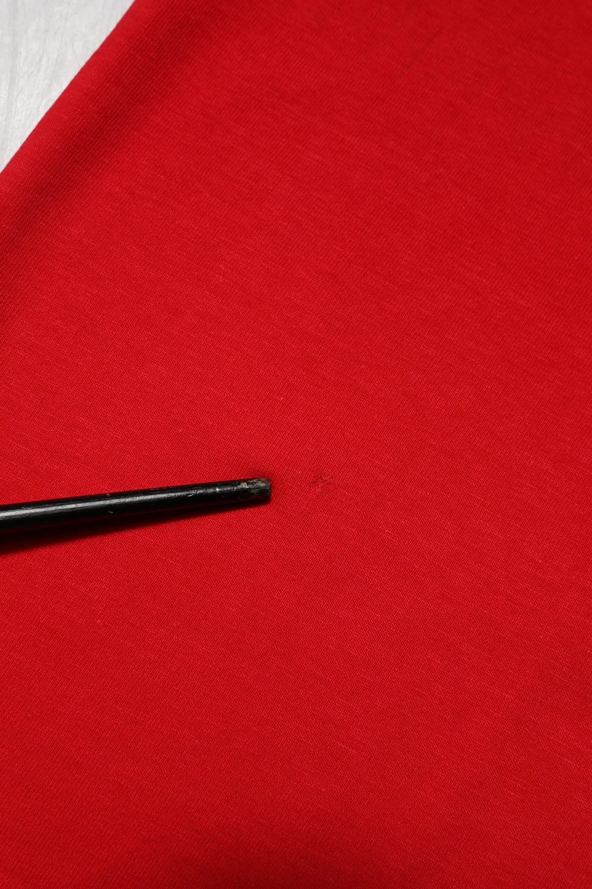 Bâtonnets noirs reposant sur tissu rouge vif à côté d un t shirt dolce & gabbana rouge à manches courtes col rond
