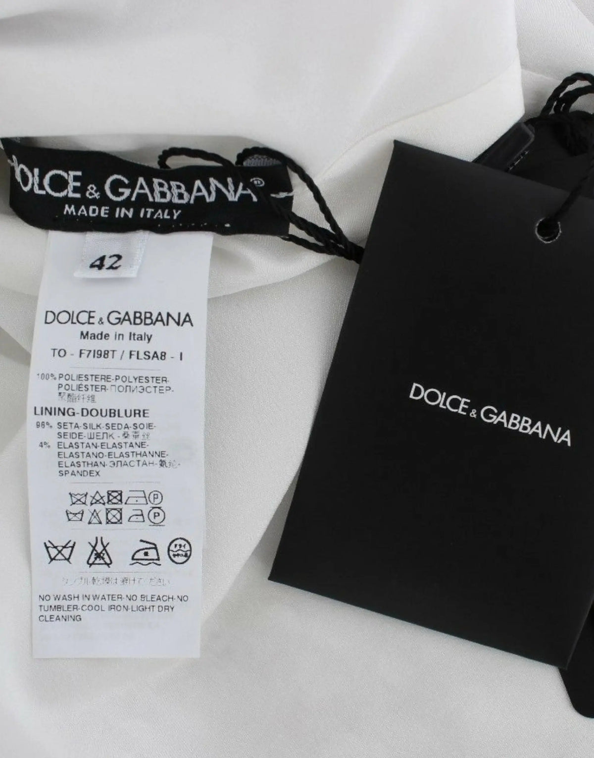 Étiquette blanche dolce & gabbana avec logo noir et instructions d’entretien sur blouse t-shirt argentée à sequins