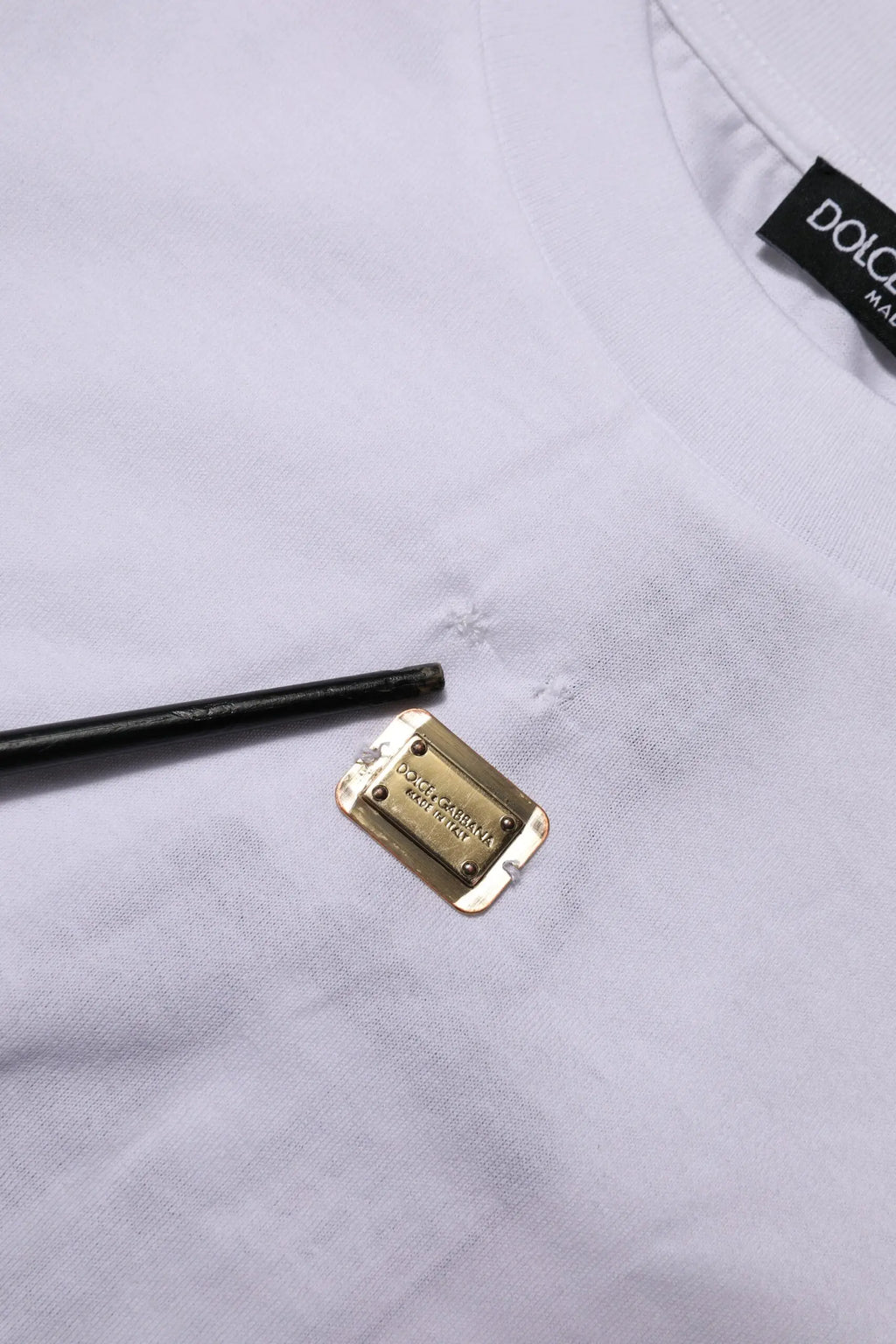 Étiquette rectangulaire en métal doré gravée dolce & gabbana sur t shirt blanc en coton à manches courtes col rond