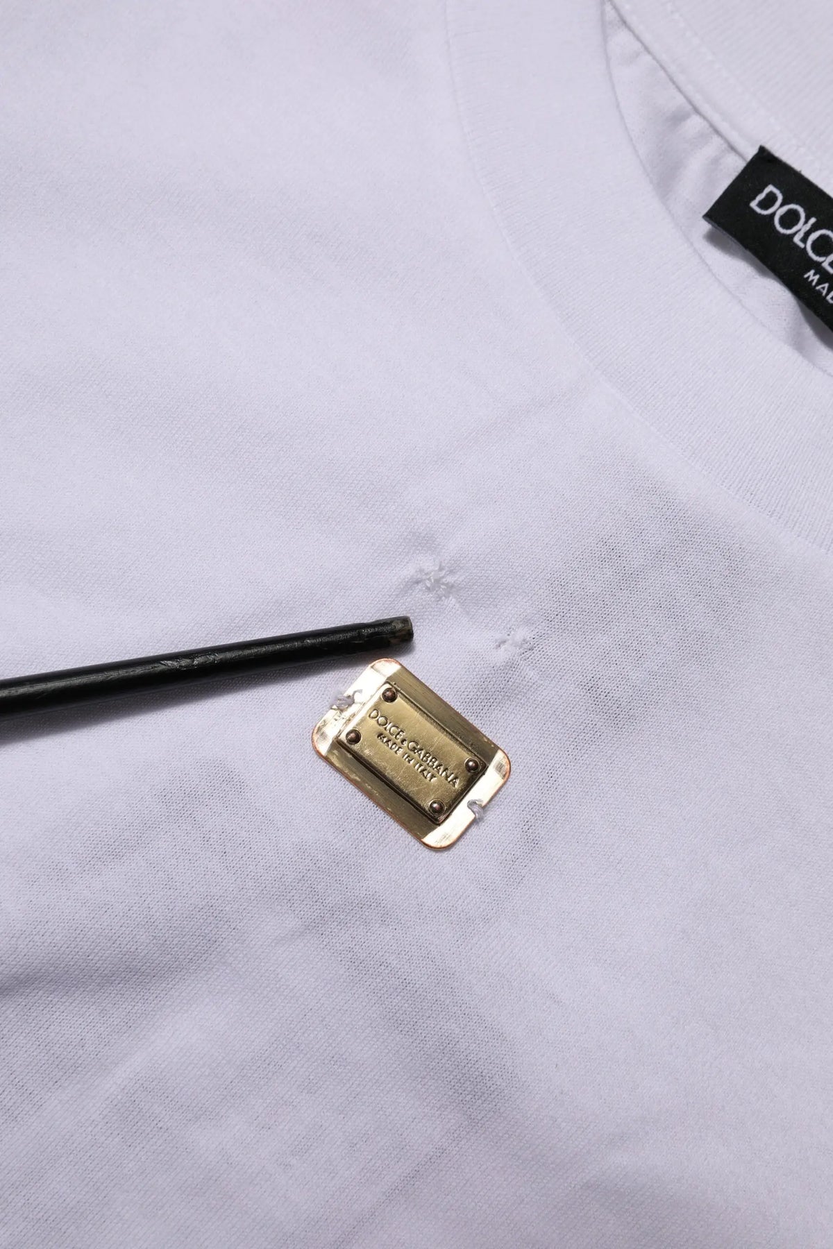Étiquette rectangulaire en métal doré gravée dolce & gabbana sur t shirt blanc en coton à manches courtes col rond